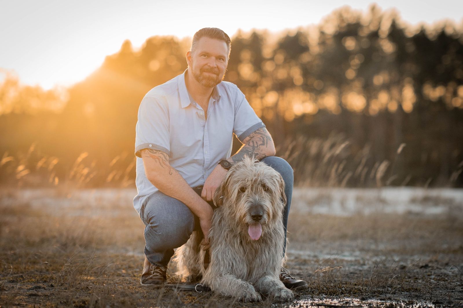 Dennis Rosenboom hockt im Gegenlicht neben seinem Hund Dexter