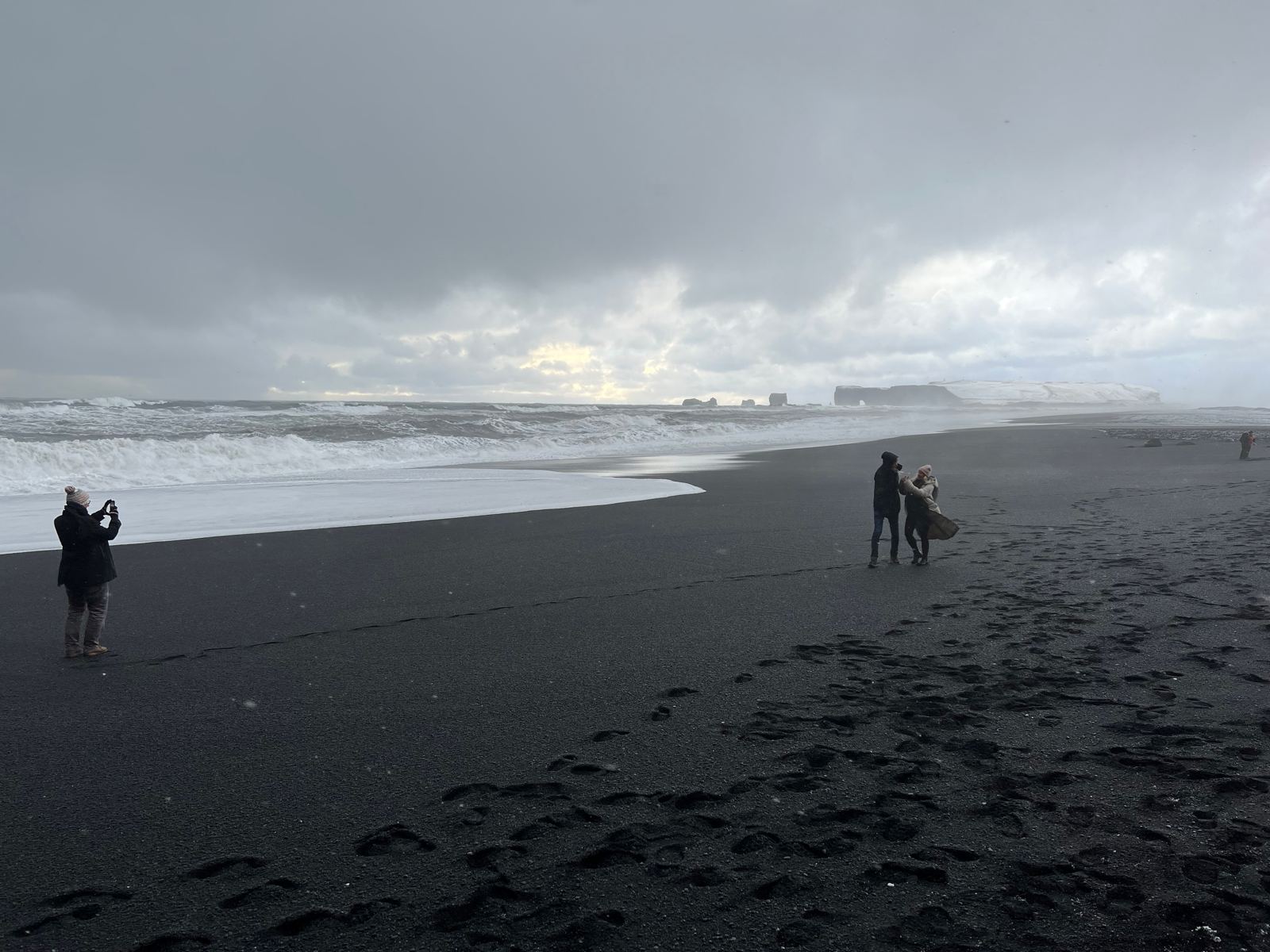 Schwarzer Strand mit Brandung im Schnee